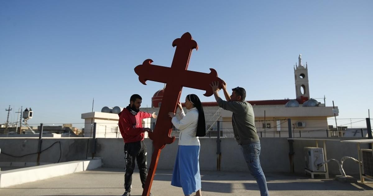 عراقيون ينصبون صليباً على كنيسة في قرة قوش في سهل نينوى استعداداً لزيارة البابا (أ ب)