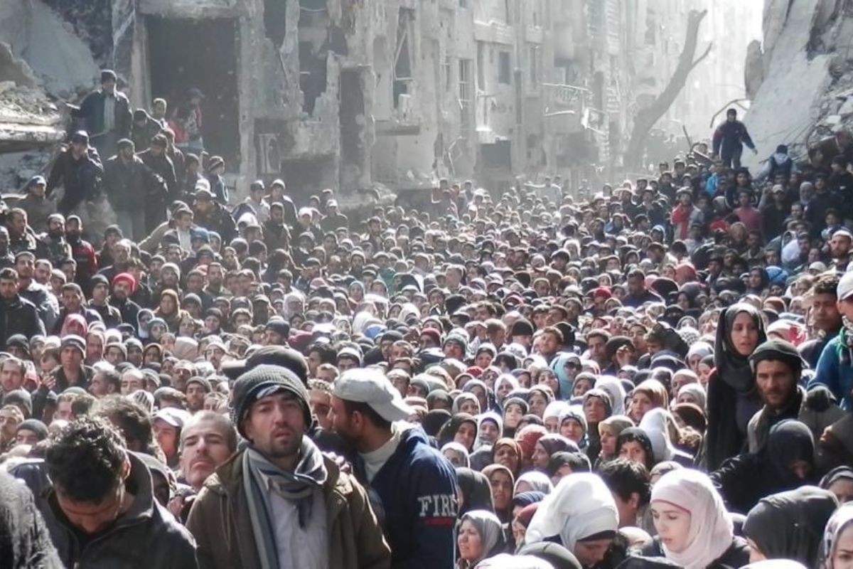 حشود كبيرة من اللاجئين ينتظرون استلام مساعدات غذائية في مخيم اليرموك في فبراير 2014/ حصار اليرموك