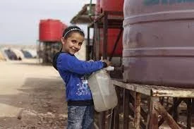 طفلة سورية تملأ مياه من خزان في أحد المخيمات في شمال شرق سوريا