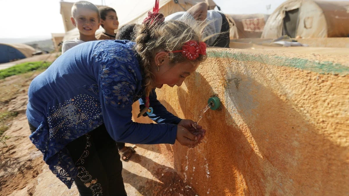 طفلة تشرب المياه في مخيم للنازحين في إدلب