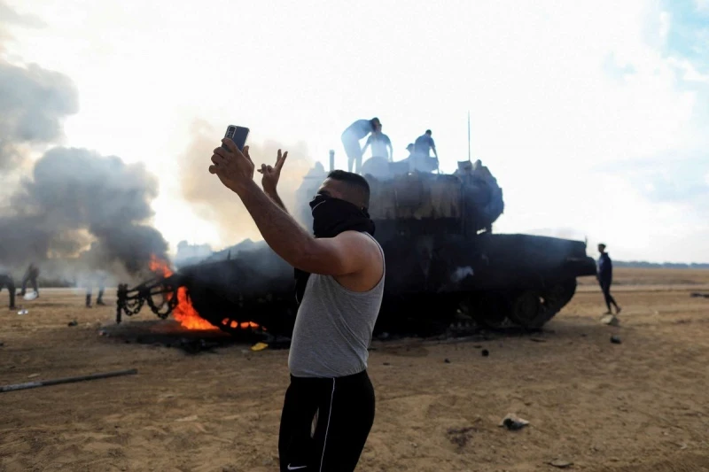فلسطيني أمام دبابة إسرائيلية محترقة