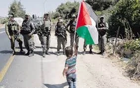 طفل فلسطيني يواجه جنود الاحتلال بعلم فلسطين