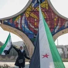 علم الثورة ترفعه احدى السوريا امام السيف الدمشقي في ساحة الامويين