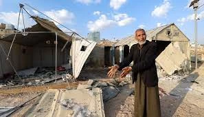 رجل مسن يشير إلى تدمير المخيم بعد القصف الروسي